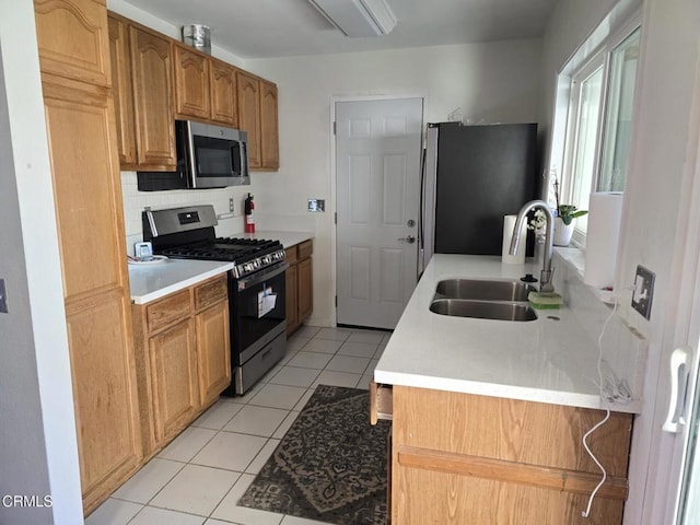 kitchen with appliances with stainless steel finishes, sink, decorative backsplash, and light tile patterned floors