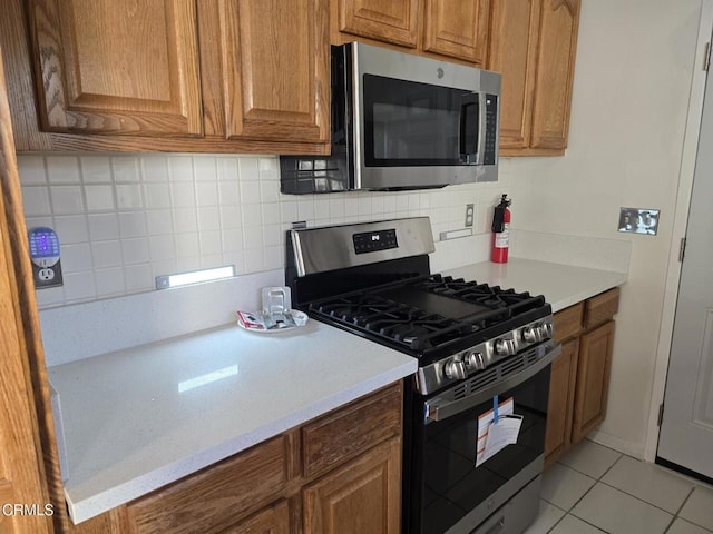 kitchen with tasteful backsplash, light tile patterned floors, and appliances with stainless steel finishes