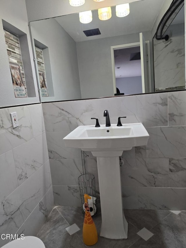 bathroom featuring sink, tile walls, and toilet