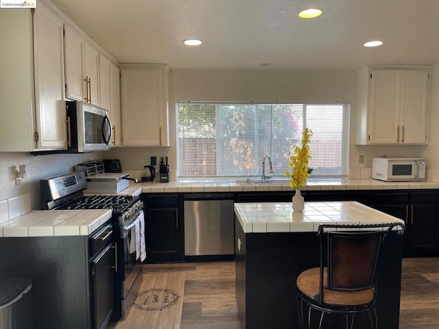 kitchen featuring tile counters, white cabinets, stainless steel appliances, and a center island