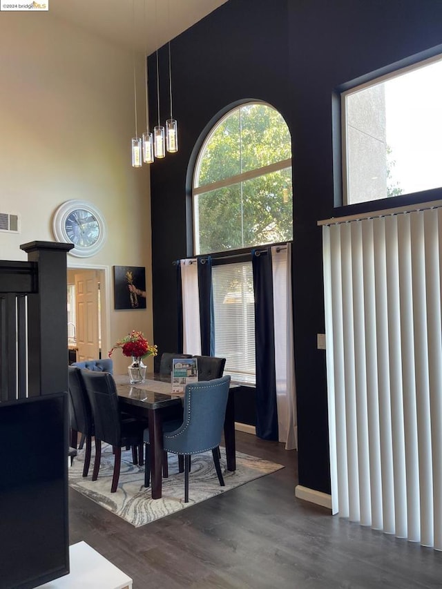 dining area featuring dark wood-type flooring and a towering ceiling