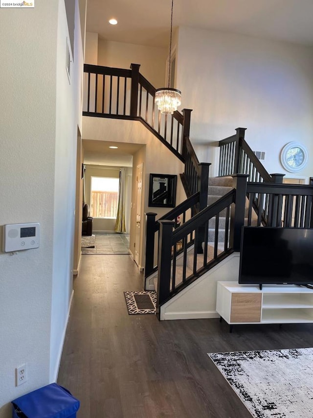 stairs featuring a high ceiling, an inviting chandelier, and hardwood / wood-style floors