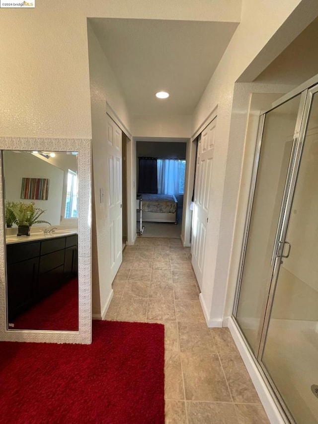 bathroom featuring walk in shower, vanity, and tile patterned flooring