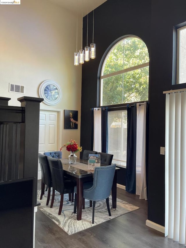 dining space with dark hardwood / wood-style floors and a towering ceiling