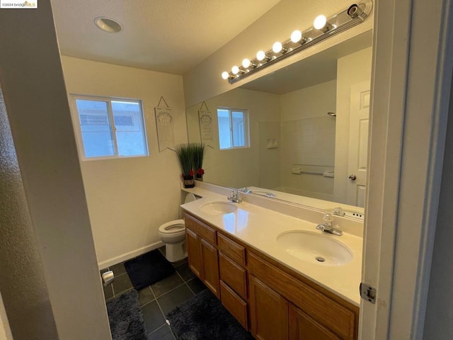 bathroom with a shower, a wealth of natural light, toilet, and vanity