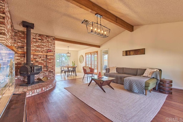 living room with a textured ceiling, an inviting chandelier, a wood stove, and hardwood / wood-style floors