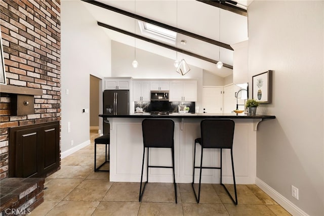 kitchen with a breakfast bar, white cabinetry, backsplash, stainless steel appliances, and kitchen peninsula