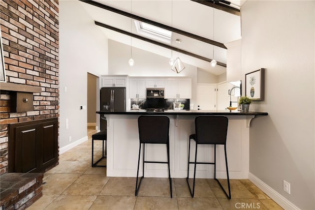 kitchen with a breakfast bar area, hanging light fixtures, appliances with stainless steel finishes, kitchen peninsula, and white cabinets