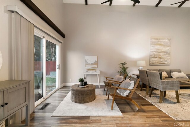 living area with ceiling fan, dark hardwood / wood-style floors, and a wealth of natural light