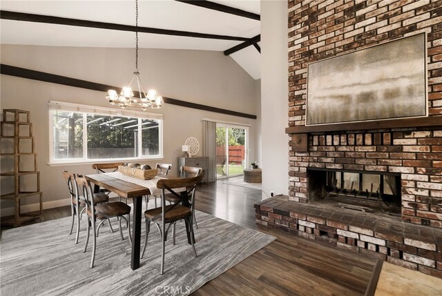 dining space with a brick fireplace, dark wood-type flooring, lofted ceiling with beams, and a chandelier