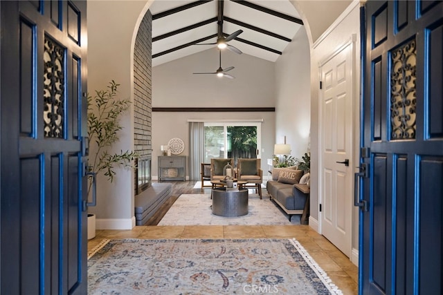 foyer with beam ceiling, high vaulted ceiling, light tile patterned floors, baseboards, and ceiling fan