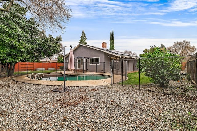 rear view of house featuring a fenced in pool