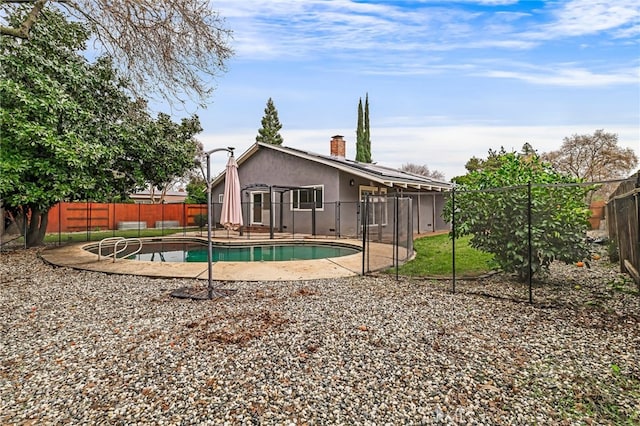 rear view of property with a fenced in pool