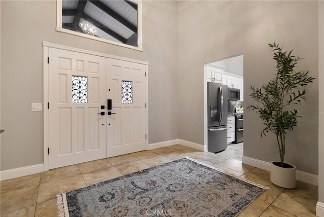 foyer entrance with light tile patterned floors and high vaulted ceiling