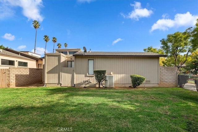 rear view of property featuring a yard and central AC unit