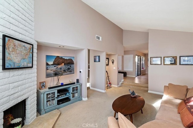 carpeted living room with a brick fireplace and high vaulted ceiling