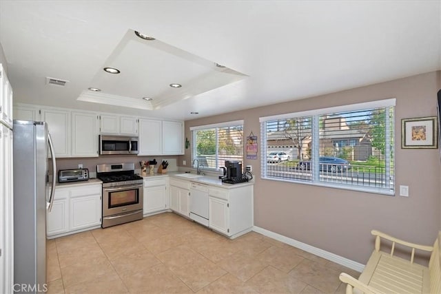 kitchen with sink, white cabinets, appliances with stainless steel finishes, and a raised ceiling