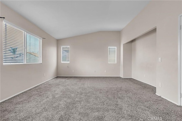 carpeted spare room featuring vaulted ceiling