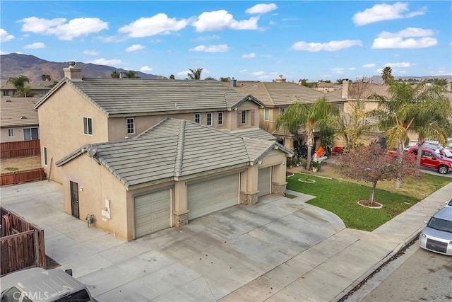 exterior space featuring a mountain view, a garage, and a lawn