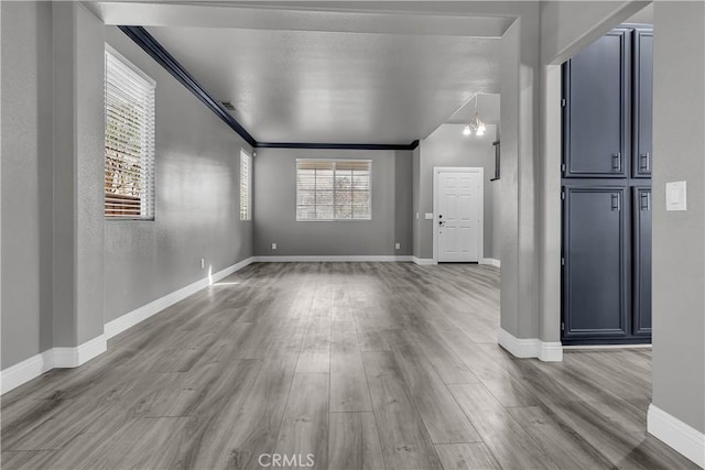 spare room featuring ornamental molding, a notable chandelier, and light wood-type flooring