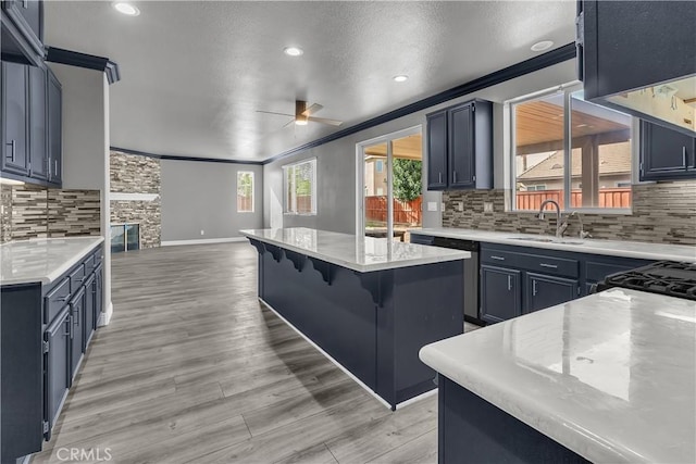 kitchen with a kitchen island, sink, ceiling fan, stainless steel dishwasher, and a breakfast bar area