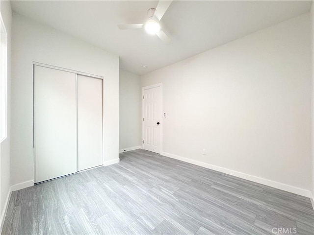 unfurnished bedroom with ceiling fan, a closet, and hardwood / wood-style flooring