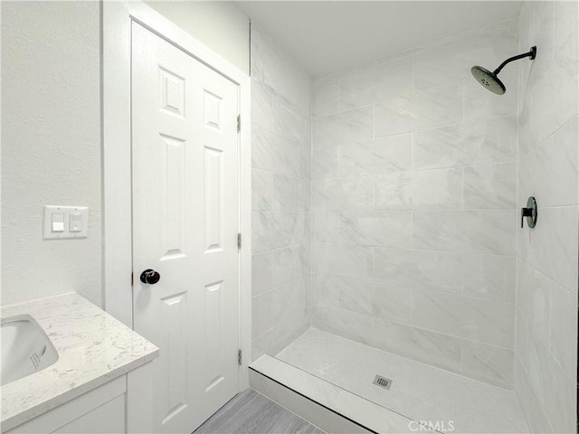 bathroom with tiled shower and vanity