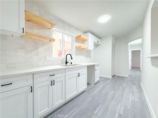 kitchen with white cabinetry, light hardwood / wood-style floors, tasteful backsplash, and sink