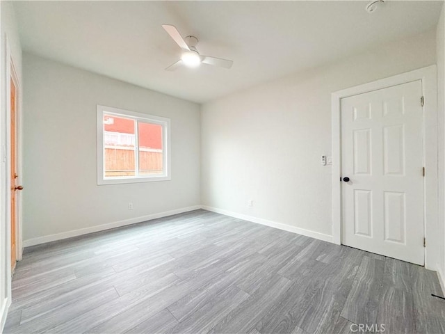 empty room with ceiling fan and light hardwood / wood-style flooring