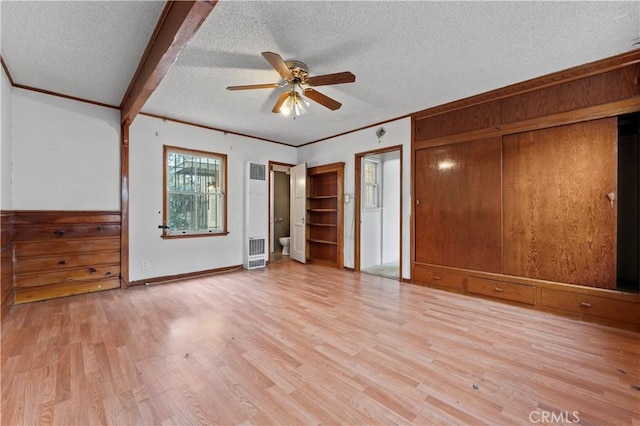 unfurnished bedroom with ceiling fan, a textured ceiling, ornamental molding, beam ceiling, and light hardwood / wood-style flooring