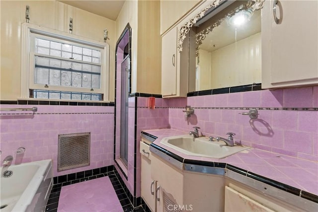 bathroom with vanity, tile patterned flooring, tile walls, and a washtub