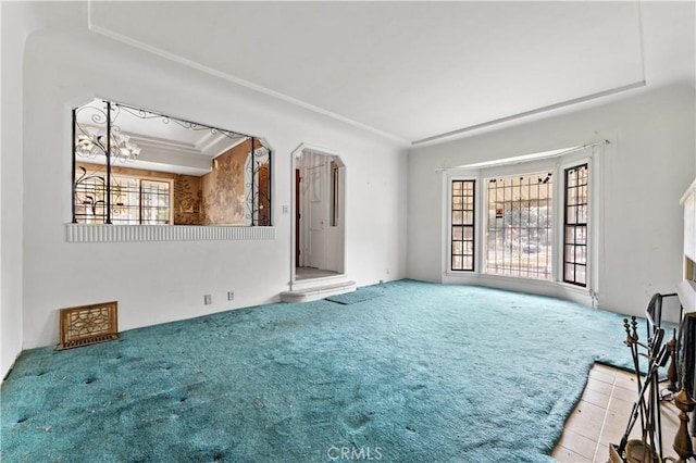 unfurnished living room featuring plenty of natural light, light colored carpet, and a raised ceiling