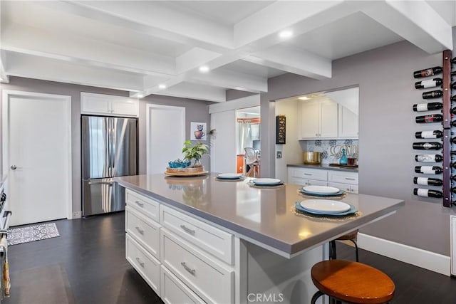 kitchen with a breakfast bar, beam ceiling, stainless steel fridge, and backsplash