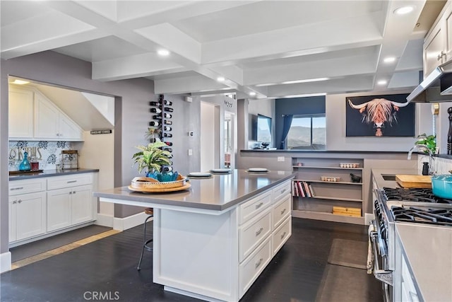 kitchen featuring sink, a kitchen breakfast bar, stainless steel range with gas stovetop, white cabinets, and a kitchen island