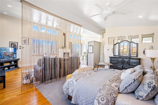 bedroom with recessed lighting, baseboards, a high ceiling, and wood finished floors