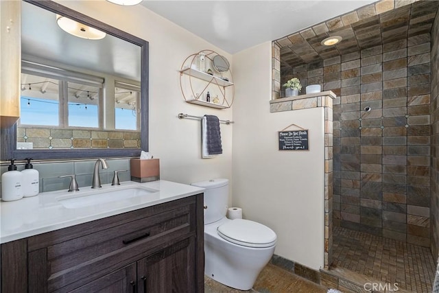 bathroom featuring vanity, tiled shower, and toilet