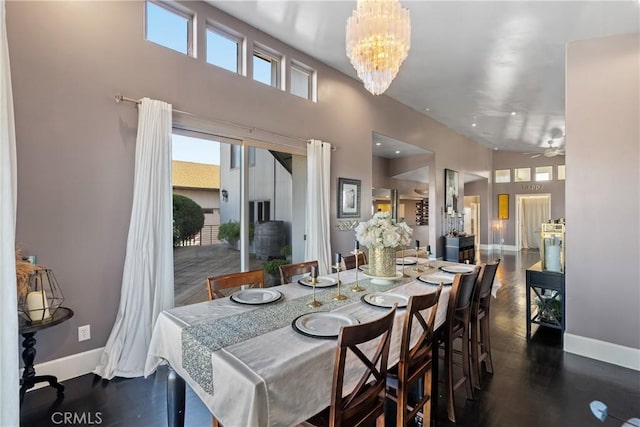 dining room with a high ceiling and ceiling fan with notable chandelier