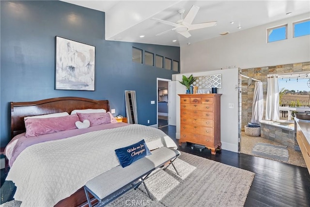 bedroom featuring access to exterior, a walk in closet, vaulted ceiling, wood finished floors, and a ceiling fan