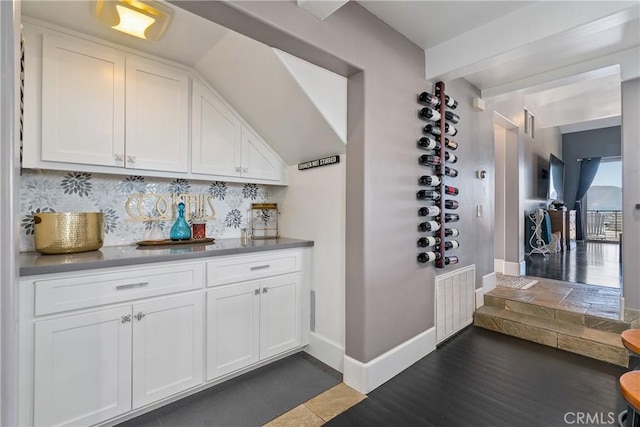 bar with white cabinetry, backsplash, and dark hardwood / wood-style flooring