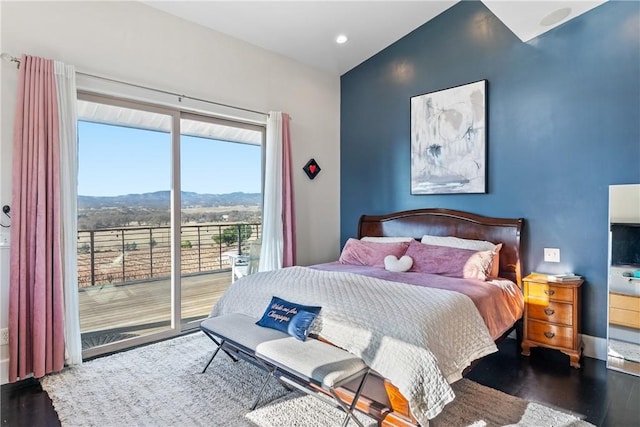 bedroom with dark hardwood / wood-style floors, a mountain view, and access to outside