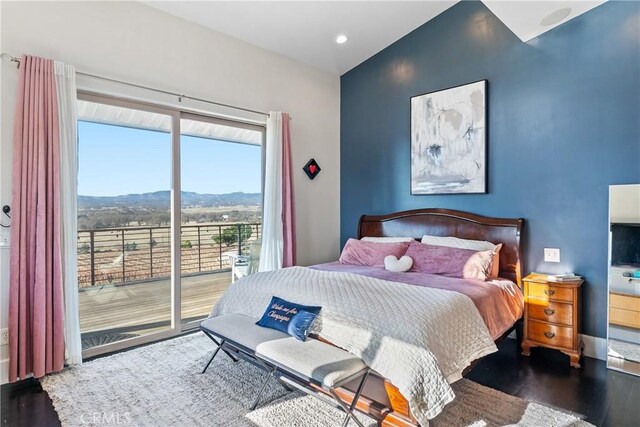 bedroom with a mountain view, wood finished floors, and access to outside