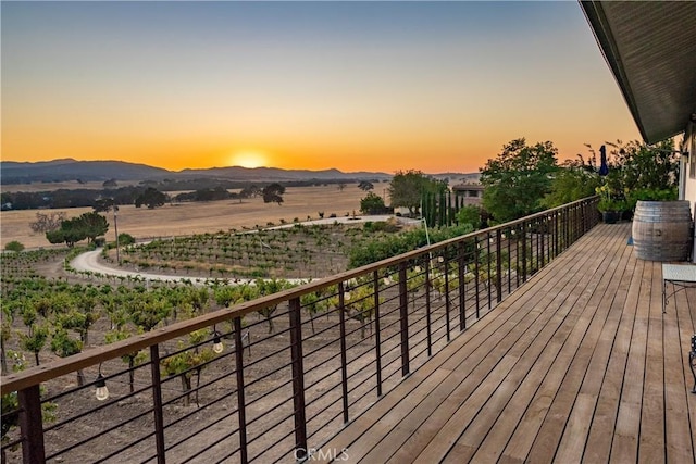 deck at dusk with a mountain view and a rural view