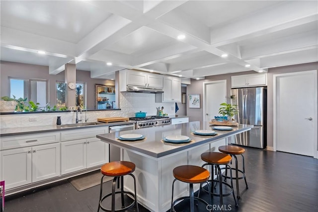 kitchen with stainless steel refrigerator, sink, a kitchen breakfast bar, stove, and a center island