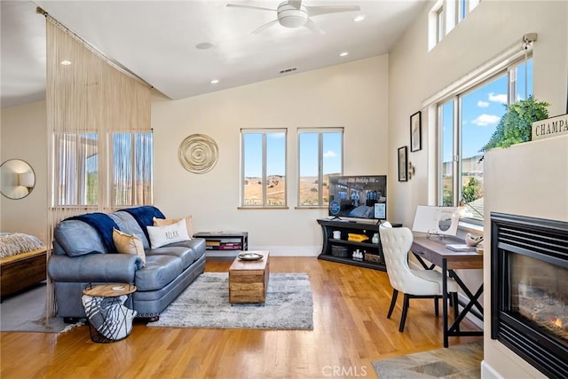 living room with vaulted ceiling, ceiling fan, and light wood-type flooring