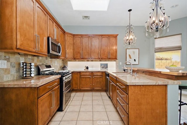 kitchen featuring stainless steel appliances, tasteful backsplash, a notable chandelier, a breakfast bar, and sink