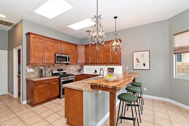 kitchen with sink, hanging light fixtures, stainless steel appliances, light tile patterned floors, and a chandelier