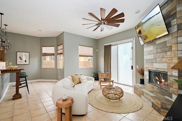 living room featuring ceiling fan, light tile patterned flooring, a tile fireplace, and a healthy amount of sunlight