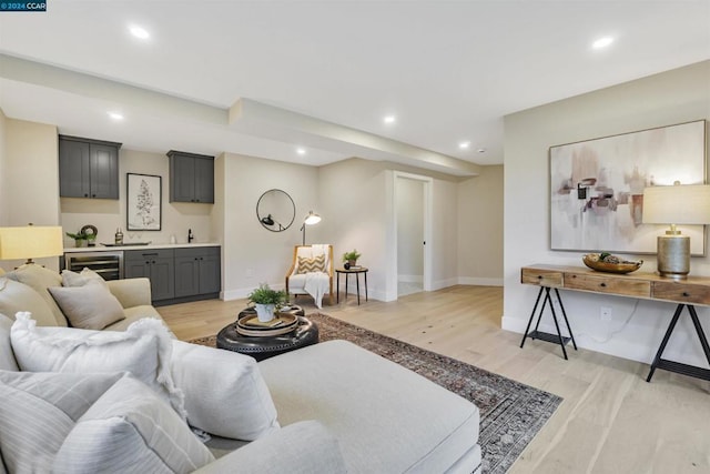 living room with bar area, wine cooler, and light hardwood / wood-style floors