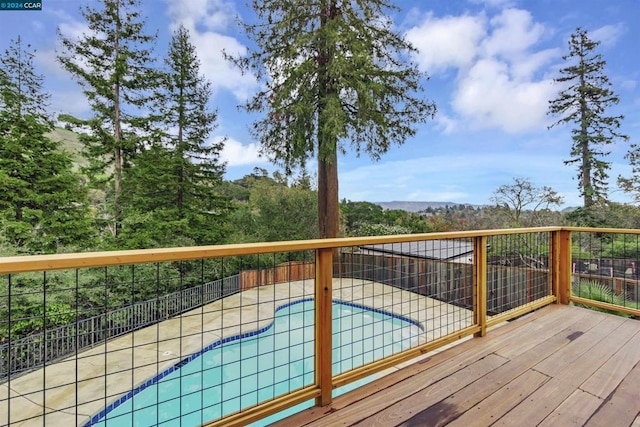 wooden terrace with a fenced in pool and a patio area