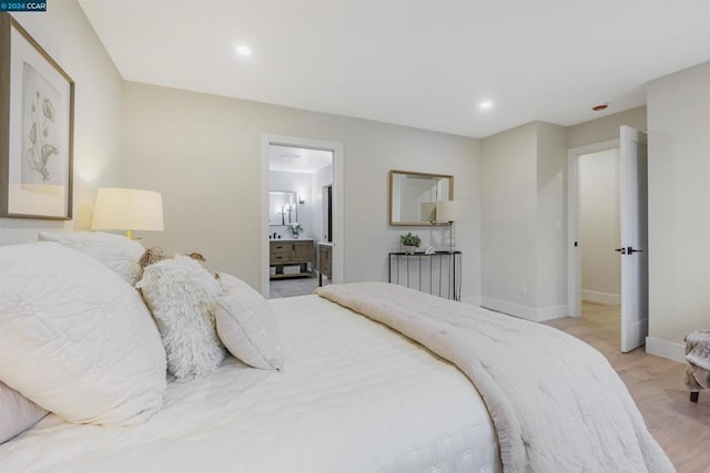 bedroom with connected bathroom and light wood-type flooring